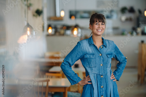 Female owner with hand on hip standing in coffee shop