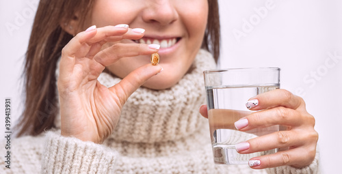 Happy woman with fish oil capsule or vitamin D supplement. Taking omega 3 or D3