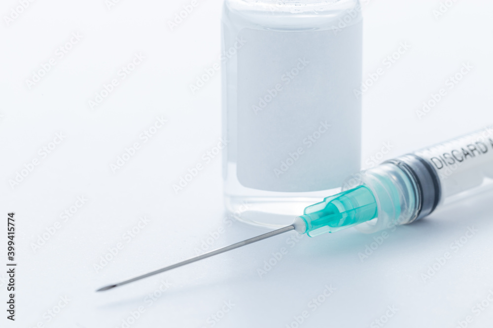 A hypodermic needle next to a vial containing a vaccine A hypodermic needle next to a vial containing a vaccine