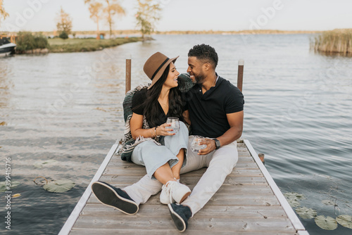 Couple with wineglass looking at each other while sitting on pier