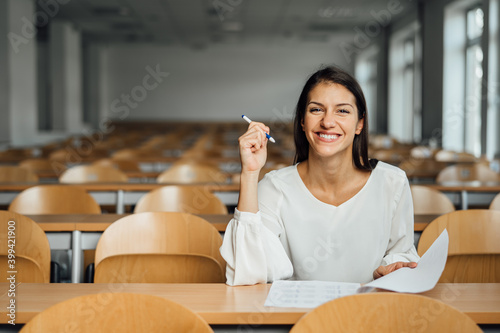 Knowledgable smiling student taking an easy exam in an empty amphitheater. An optimistic student taking an in-class test. Happy woman having stress free education evaluation.Essay exam inspiration. photo