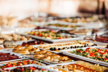 Elegant serving dishes and food warmers with various meals served for catering wedding reception in a hotel or restaurant. Buffet served by the catering service company.Appetizers in elegant serveware