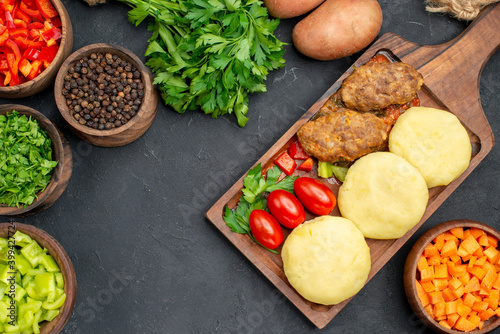 Top view of tasty cutlets with vegetables and a bunch of green on dark background