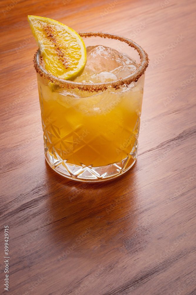 Fruit mixology with mezcal and orange slice on wooden table topper. Warm colored cocktails. Mezcal cocktail.