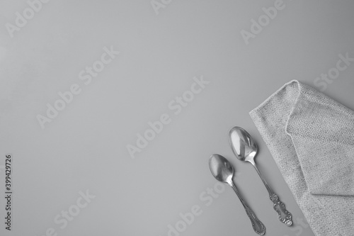 Top view of two silver spoons and a gray napkin in a gray background with copy space