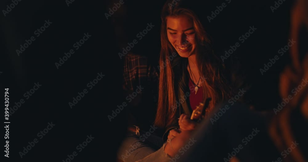 Happy friends singing playing ukulele at beach night bonfire Happy friends singing playing ukulele at beach night bonfire