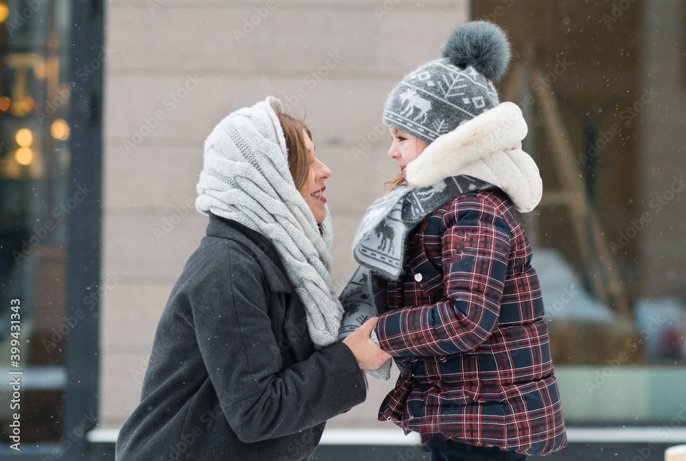 Little daughter looking at mother with love in winter city Little daughter looking at mother with love in winter city