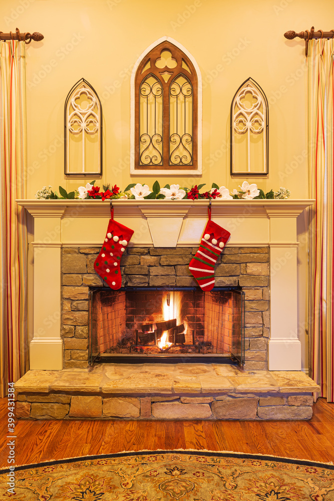 Two fun Christmas stockings hang on the mantle of a beautiful stone  fireplace with cathedral window decor. Stock Photo | Adobe Stock