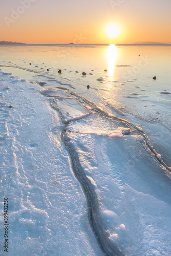Landscape sea covered with ice with cracks during sunset. Winter seascape