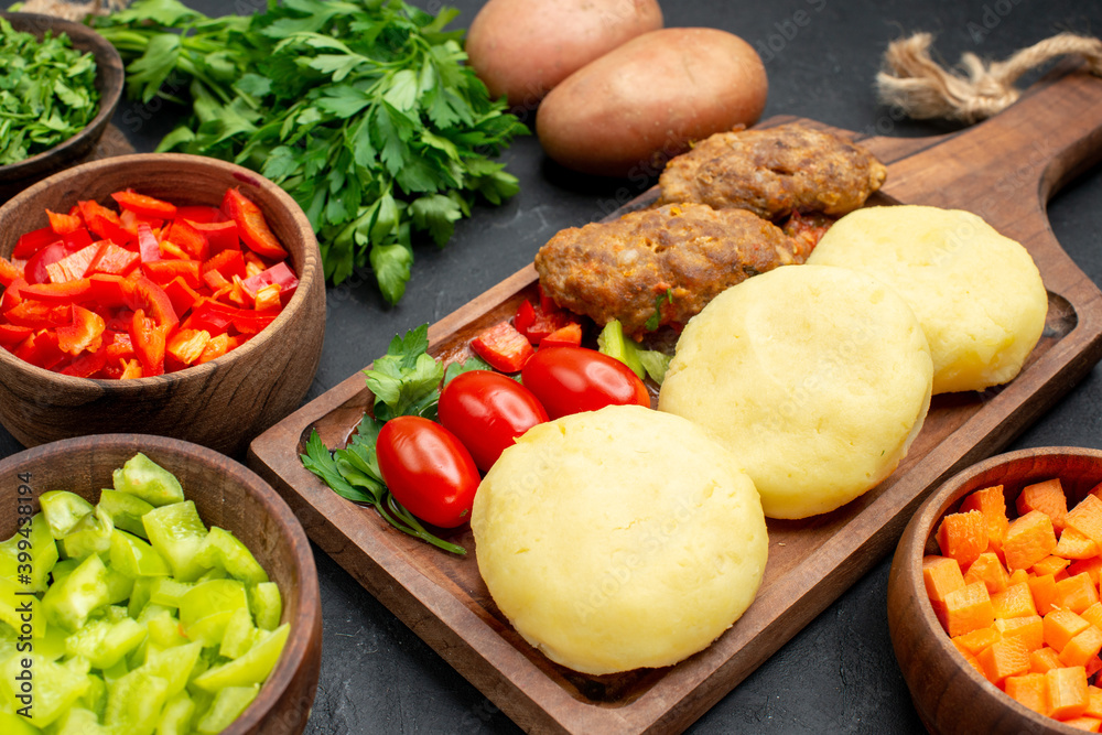 Horizontal view of tasty cutlets with vegetables and a bunch of green on dark table Horizontal view of tasty cutlets with vegetables and a bunch of green on dark table