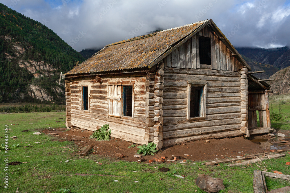 Fototapeta premium Beautiful wooden abandoned log house on mountains background