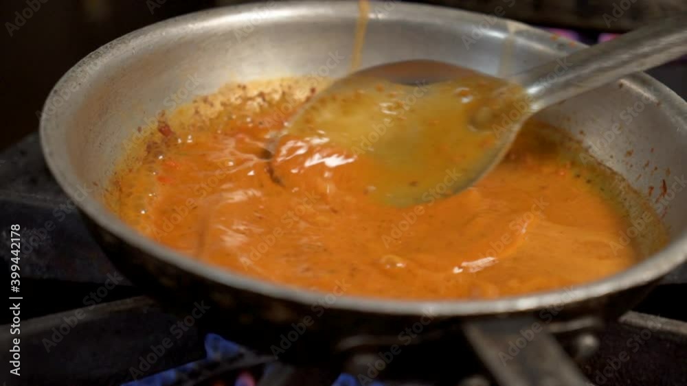 Spoon stirs bubbling red sauce in stainless skillet on stove top, slow motion HD Spoon stirs bubbling red sauce in stainless skillet on stove top, slow motion HD