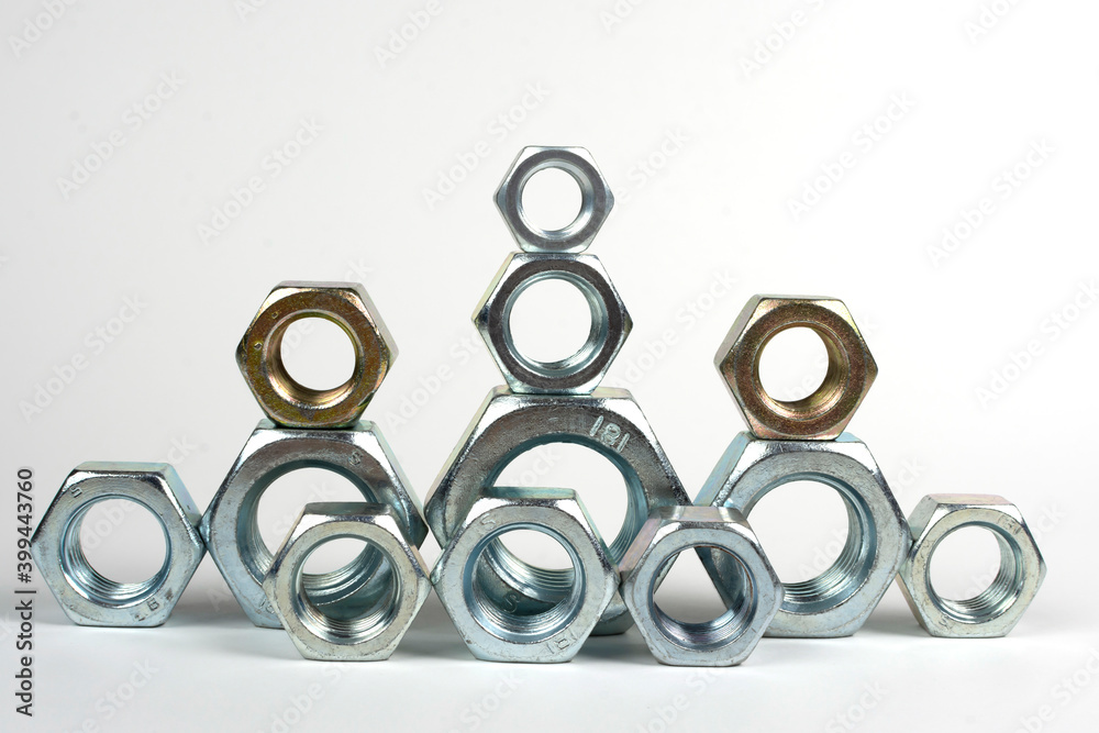 many metal nuts stacked on a white background many metal nuts stacked on a white background