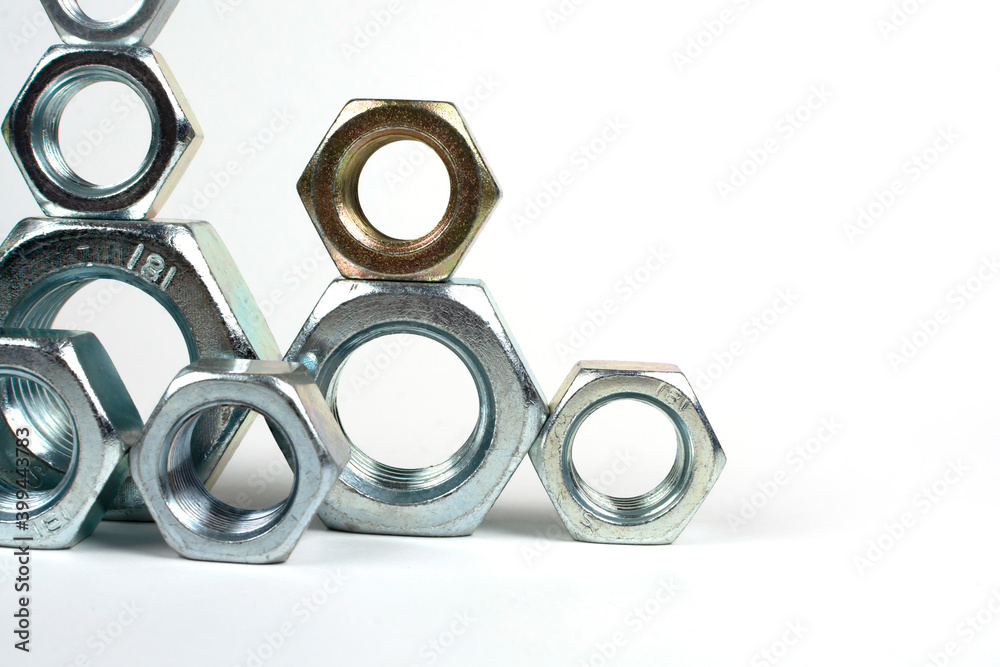 many metal nuts stacked on a white background many metal nuts stacked on a white background