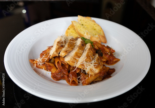Grilled Chicken in a spicy chili and olive tomato sauce served with penne pasta, garlic bread and parmesan
