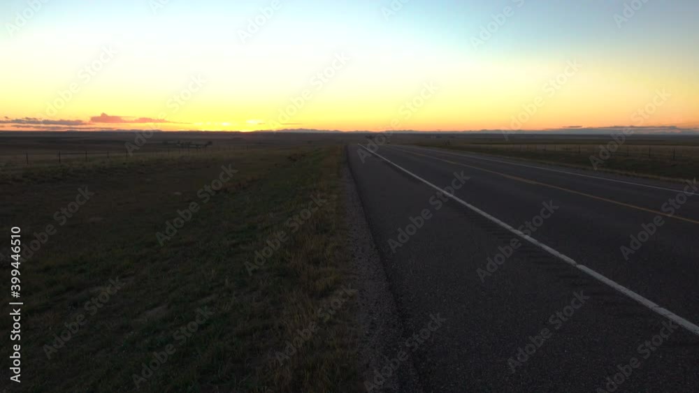 Car Drives and Disappears into the Horizon on Long Empty Kansas Highway Road at Dusk in the Middle of Nowhere, Farm Country Car Drives and Disappears into the Horizon on Long Empty Kansas Highway Road at Dusk in the Middle of Nowhere, Farm Country