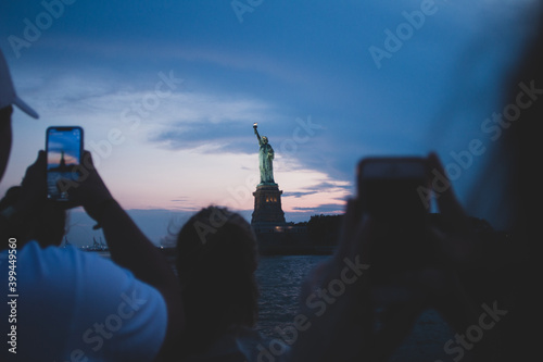 People taking a photo of Statue Of Liberty at sunset