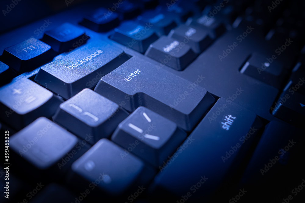 Black computer keyboard. The backspace, enter, and shift keys are illuminated. Close-up of computer keyboard buttons. Peripherals for the PC. Black computer keyboard. The backspace, enter, and shift keys are illuminated. Close-up of computer keyboard buttons. Peripherals for the PC.