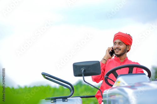 Young Indian farmer talking on smartphone at field
