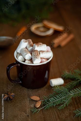 Christmas winter cocoa with marshmallow and lollipop in the shape of a Christmas tree in a brown cup on a wooden background. Vertical photo. Selective focus.