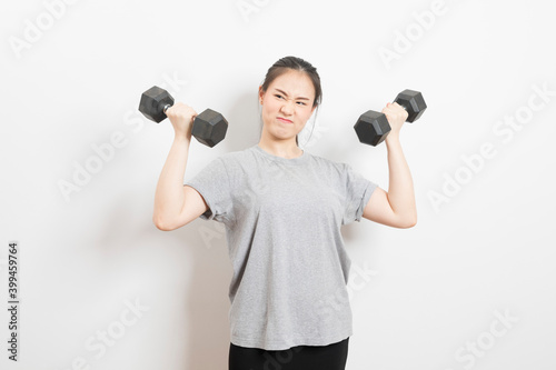 Beautiful young Asian woman lifting dumbbells smiling and energetic isolated over white background. Healthy lifestyle.