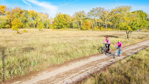 Family on bikes autumn cycling outdoors, active mother and kid on bicycles, aerial view of happy family with child in fall park from above, sport and fitness concept 