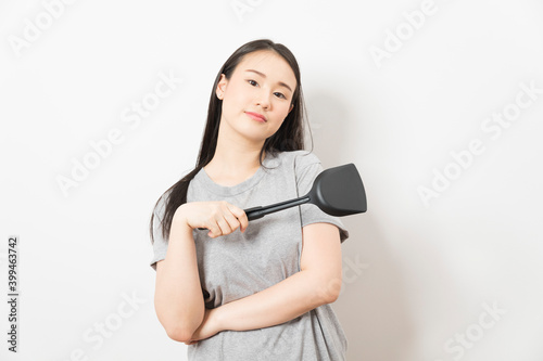 Asian woman holding ladle ready for cooking isolated on white background.