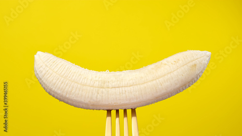 banana on golden fork close up. yellow background