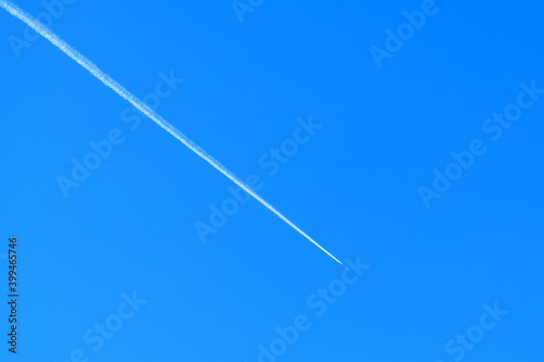 White contrails of a jet against a clear blue sky