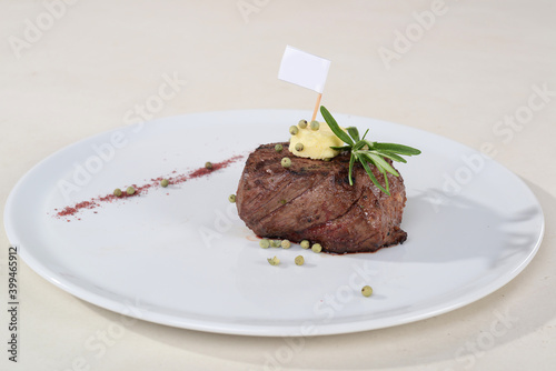juicy minien steak on a white plate with a flag on a white background

