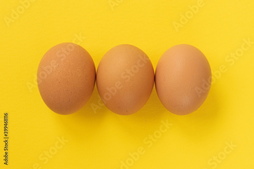 Close-up view of raw chicken eggs on yellow background.