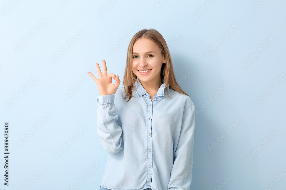 Beautiful young woman showing OK gesture on color background Beautiful young woman showing OK gesture on color background