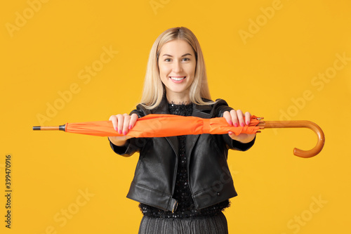 Stylish young woman with umbrella on color background