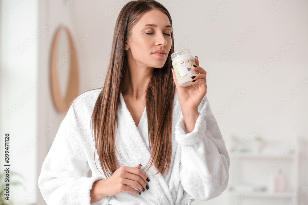 Beautiful young woman with coconut oil in bathroom Beautiful young woman with coconut oil in bathroom