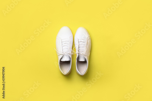 Stylish white sneakers on yellow background. Minimal flat lay. Demonstrating trendy Color of the Year 2021. Illuminating Yellow and Ultimate Gray