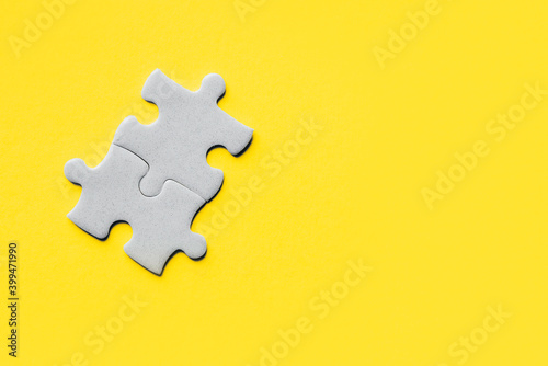 Closeup of jigsaw puzzle piece. Demonstrating trendy Color of Year 2021. Illuminating Yellow and Ultimate Gray. Duotone. Puzzle pieces on yellow background. idea, sign, symbol, concept of connecting