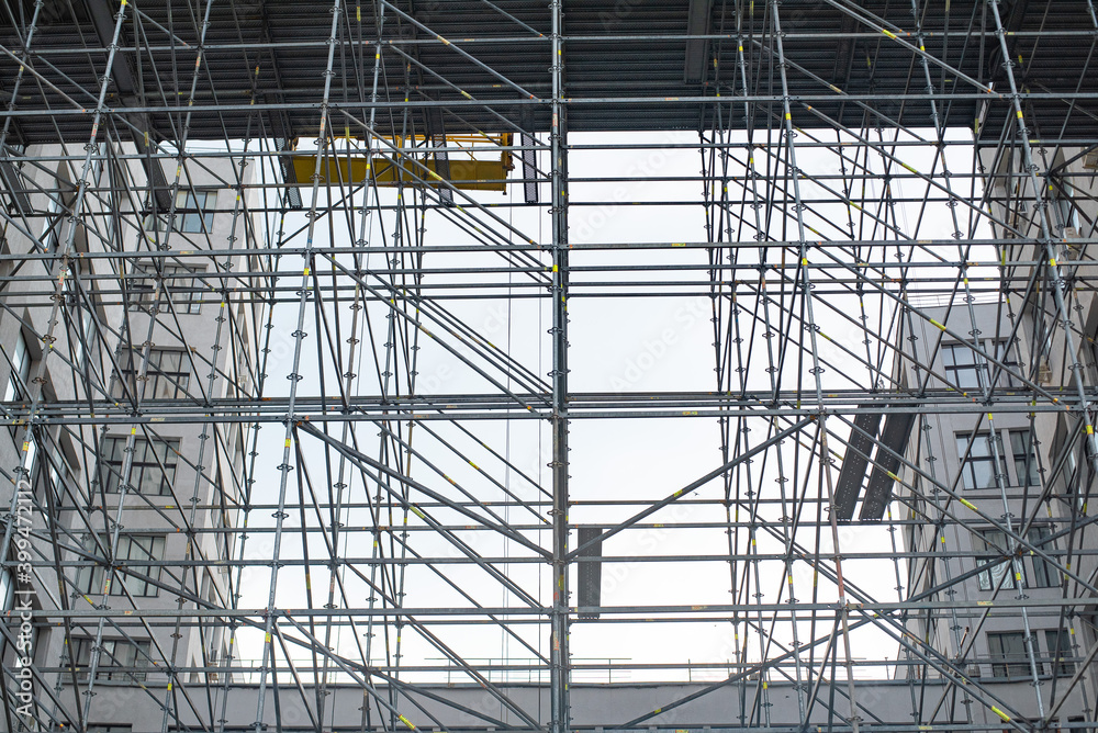 Extensive scaffolding providing platforms for work in progress on a tall building under construction with scaffolds. Extensive scaffolding providing platforms for work in progress on a tall building under construction with scaffolds.