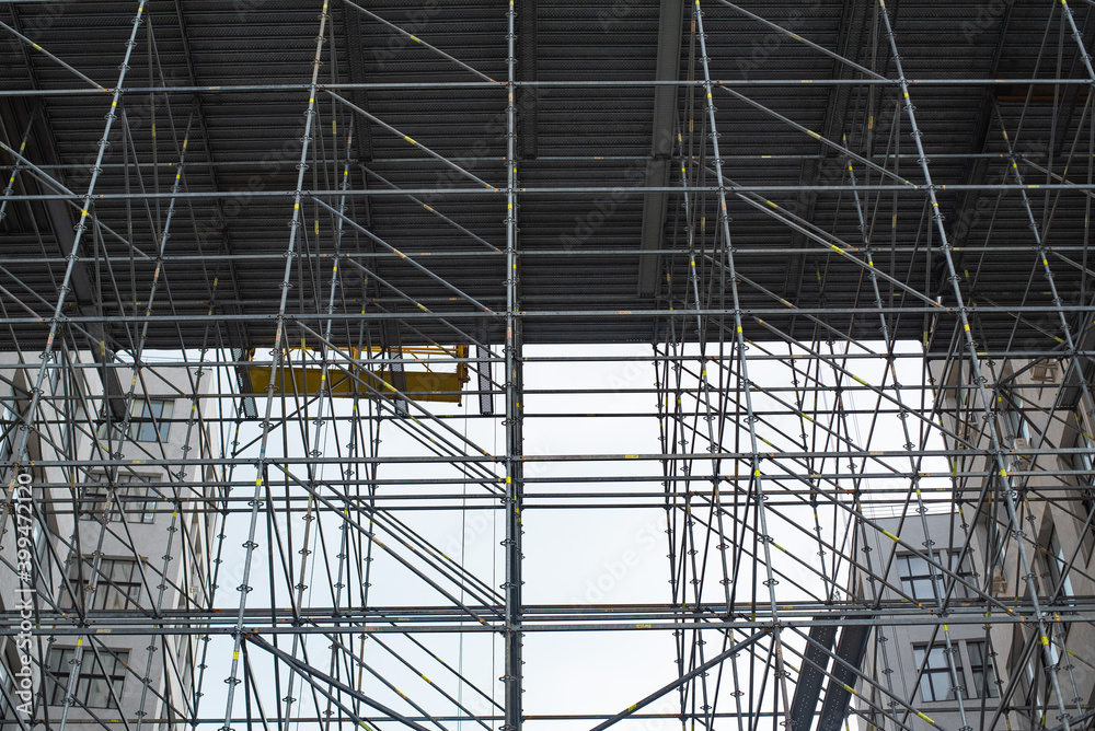 Extensive scaffolding providing platforms for work in progress on a tall building under construction with scaffolds.