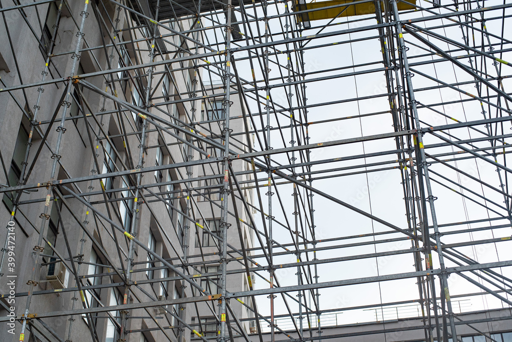 Extensive scaffolding providing platforms for work in progress on a tall building under construction with scaffolds. Extensive scaffolding providing platforms for work in progress on a tall building under construction with scaffolds.