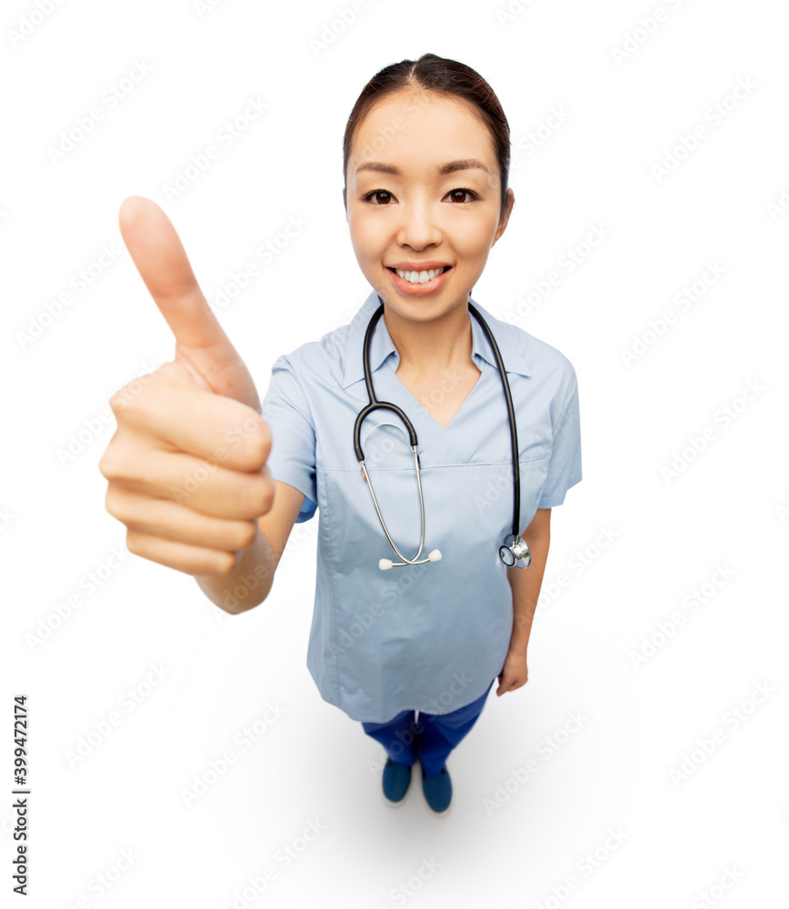 medicine, profession and healthcare concept - happy smiling asian female doctor or nurse in blue uniform coat with stethoscope showing thumbs up over white background medicine, profession and healthcare concept - happy smiling asian female doctor or nurse in blue uniform coat with stethoscope showing thumbs up over white background