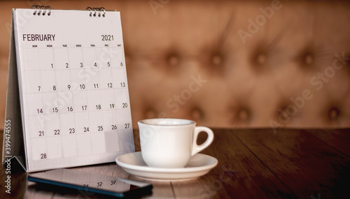 Calendar, mobile, coffee cup Placed on an old wooden table is a planning idea for success.