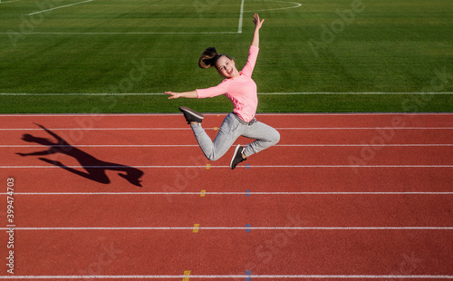 Energy inside her. full of energy. workout on fresh air outdoor. confident and free. teen girl jumping on stadium. kid in sportswear. child do exercise on racing track. healthy childhood © be free