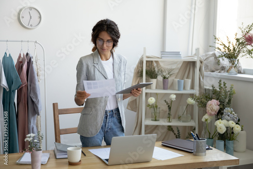 Choosing only the best. Young woman tailor designer comparing samples of textile colors offered by suppliers. Professional flower arranger pondering thinking making choice preparing to order materials photo