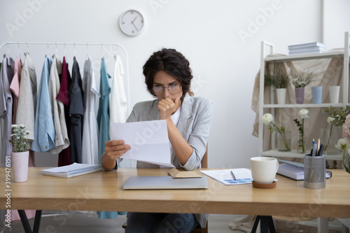 Must be a way out. Worried young female dressmaker designer florist thinking on postal letter informing about debt. Anxious self employed enterpreneur pondering on official refusal in loan from bank photo
