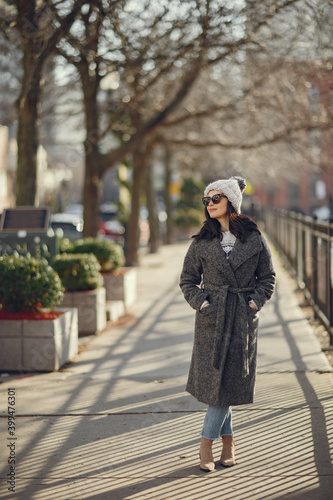 Elegant girl walk in a winter city. Woman in a white knited sweater. Beautiful lady with dark hair.