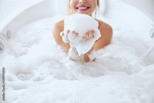 Charming young woman playing with foam in bath photo