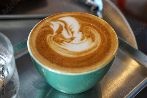 Close up ceramic mug of hot latte art coffee on metal tray