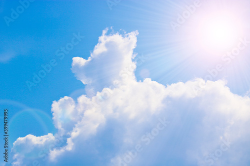 Cumulus and cirrus clouds and bright sunbeams against the blue sky. Atmospheric phenomenon, weather, summer.