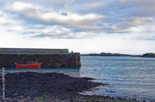 A small wooden Fishing boat with a reed hull moored up alongside the traditional old stone Quay at Catterline, on the East Coast of Scotland. photo