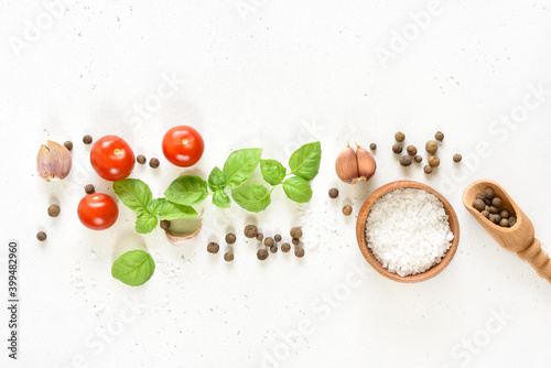 Fresh basil and spices on white stone background